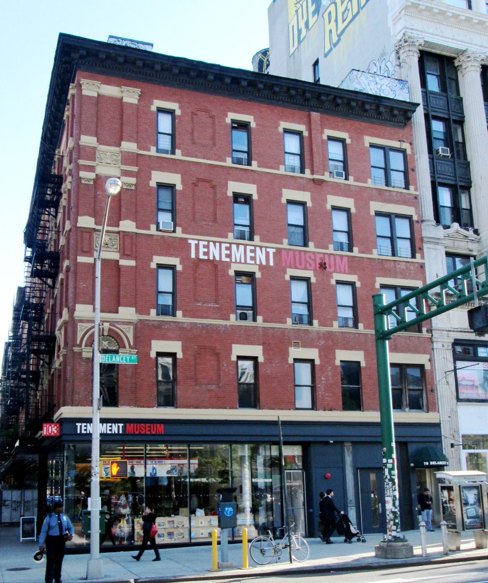 Red brick building on a street corner with Tenement Museum lettering above a glass storefront