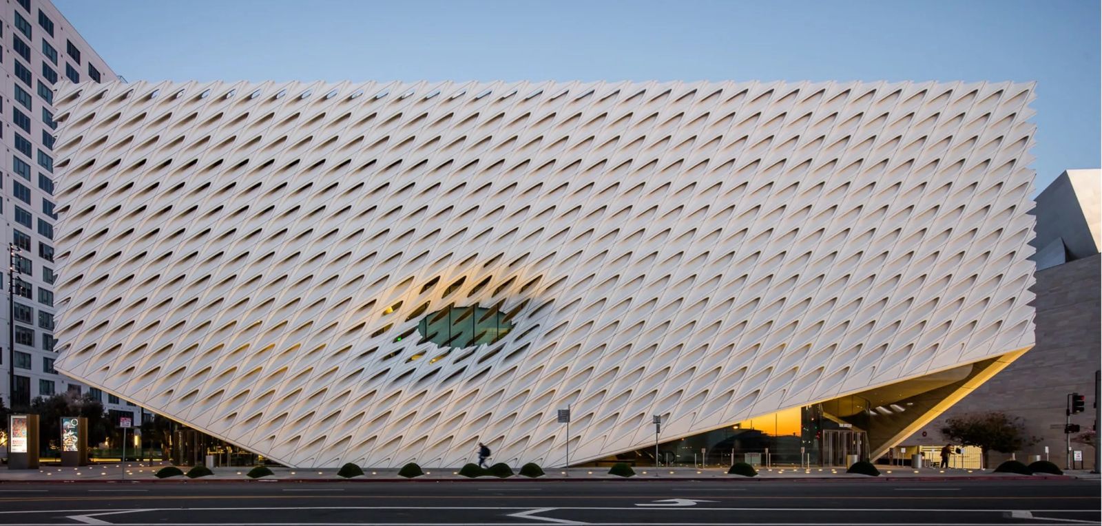The museum's white, honeycomb-textured exterior with an opening in its facade under a clear sky.