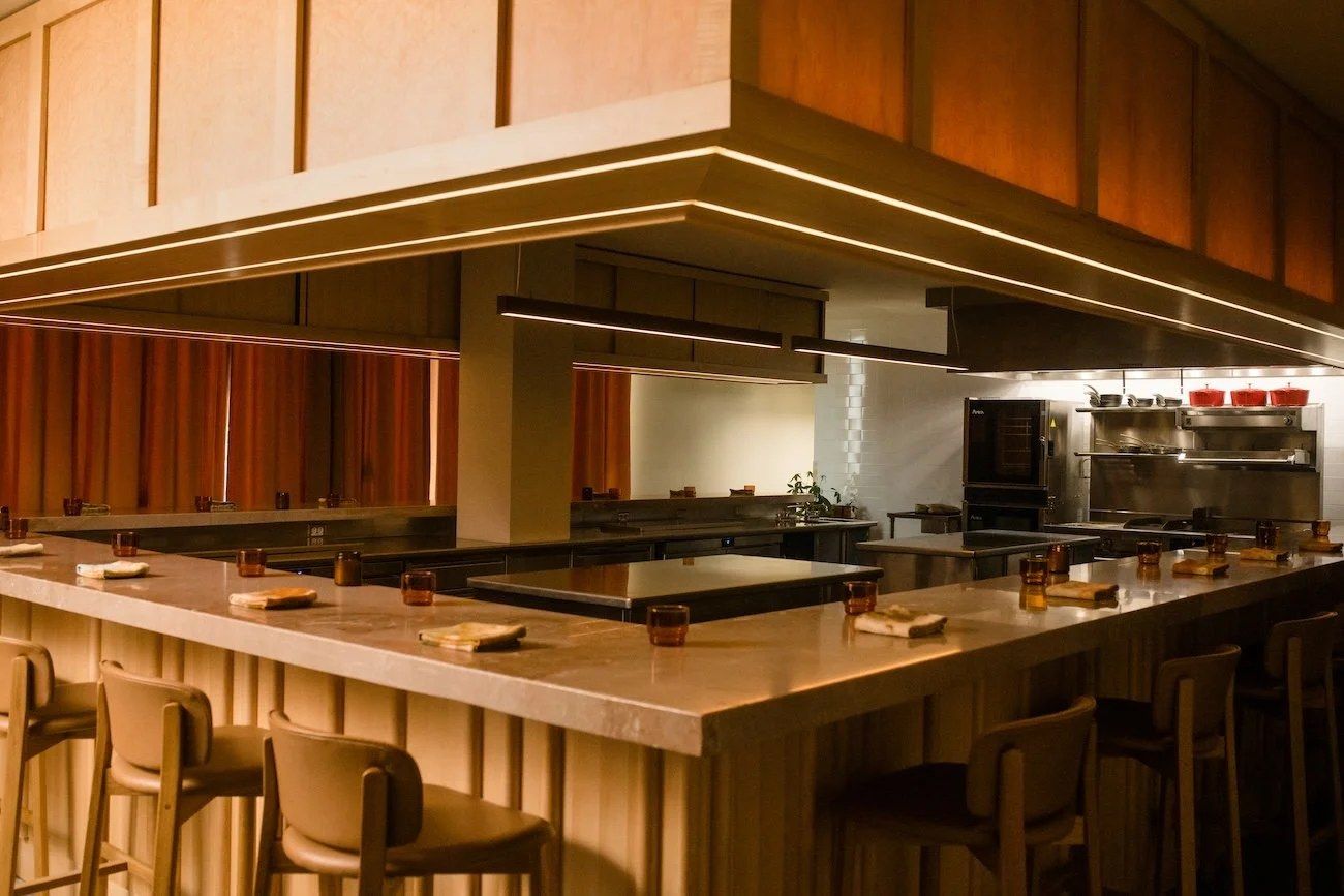 Wooden counter seating around an open kitchen with warm wood paneling