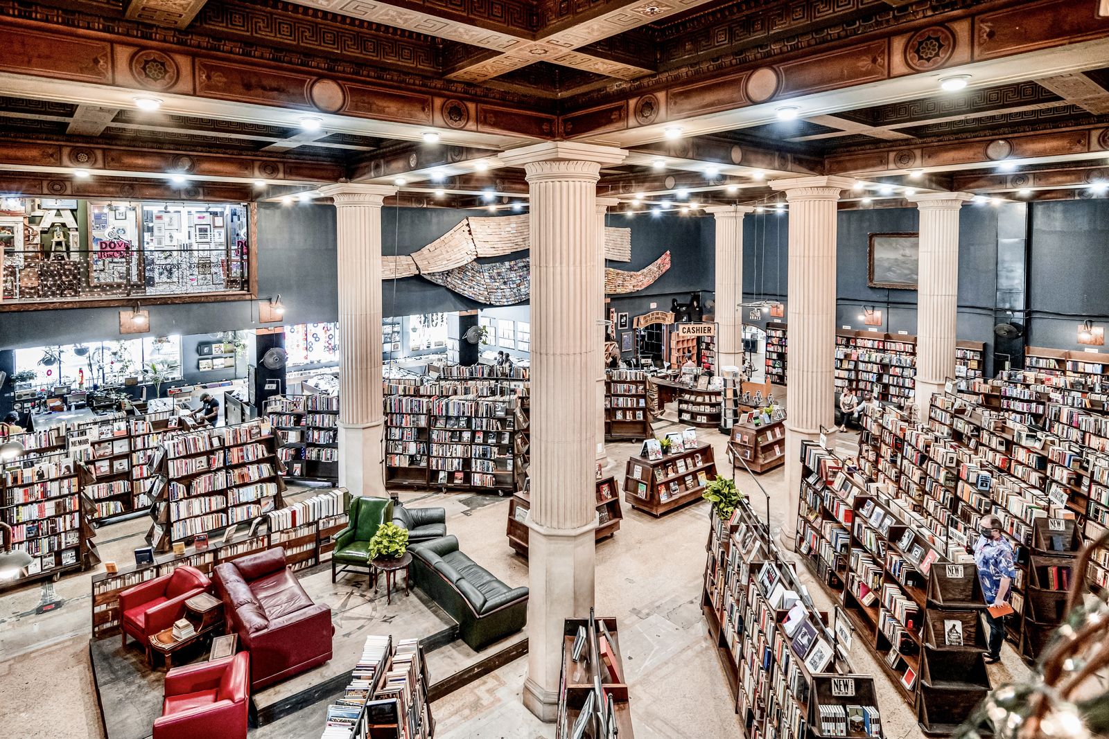 Wide view of The Last Bookstore's main floor with columns, bookshelves and red sofas