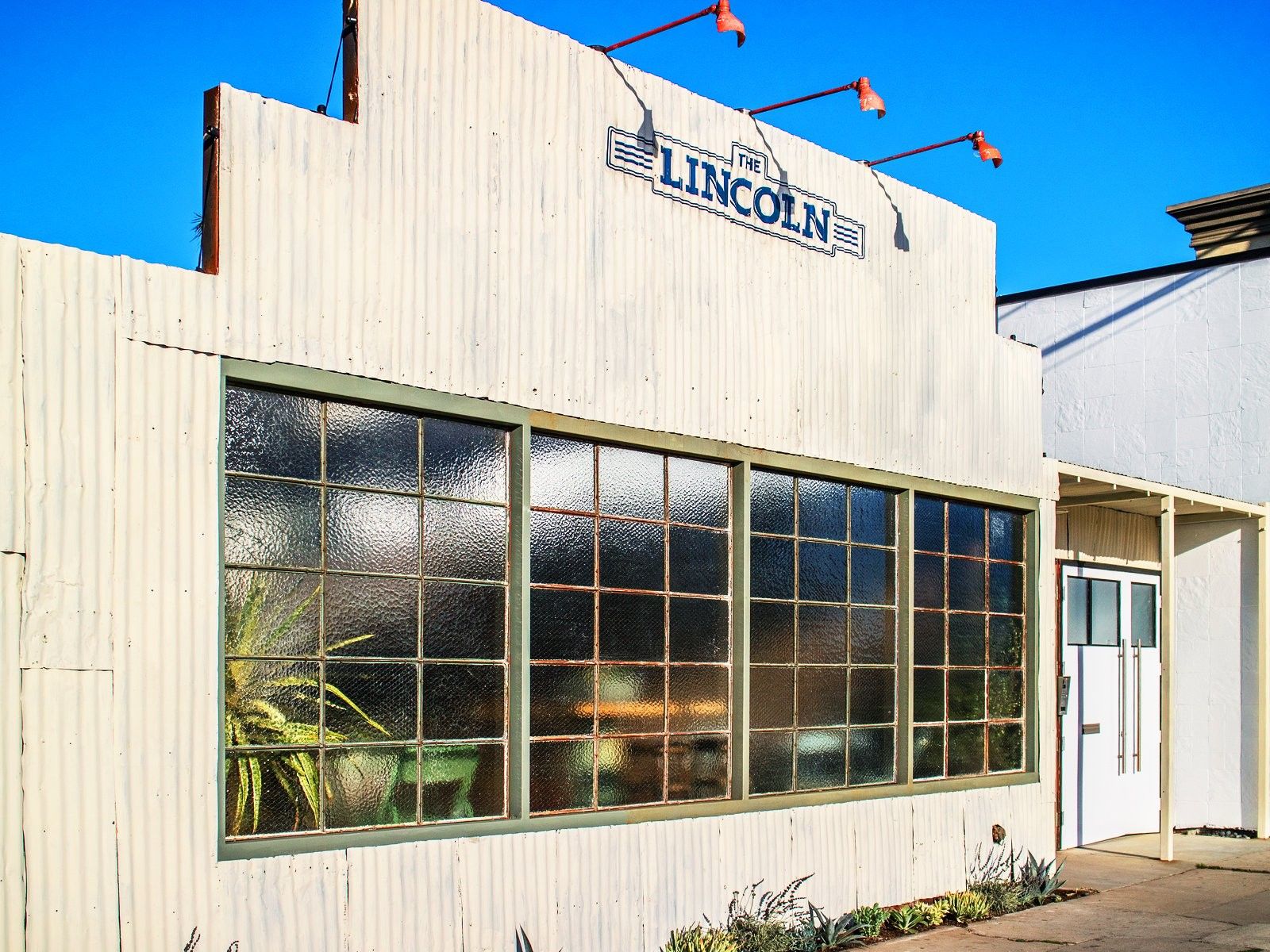 The white single-story exterior of The Lincoln, with its sign above a row of paned windows.