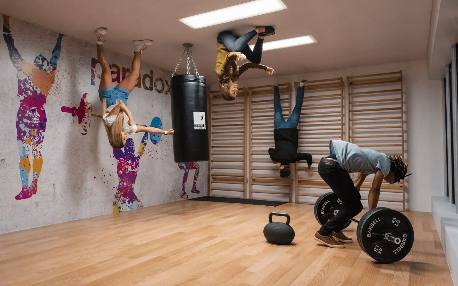 Visitors posed on an illusion room so they appear upside down in a gym-themed space