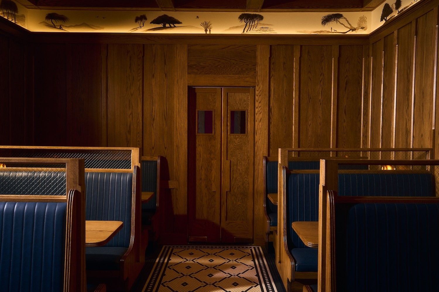 Navy leather booths along a wood-paneled wall, with a patterned tile floor.