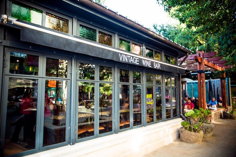 Glass-fronted wine bar exterior with a Vintage Wine Bar sign above the windows and a patio beside it