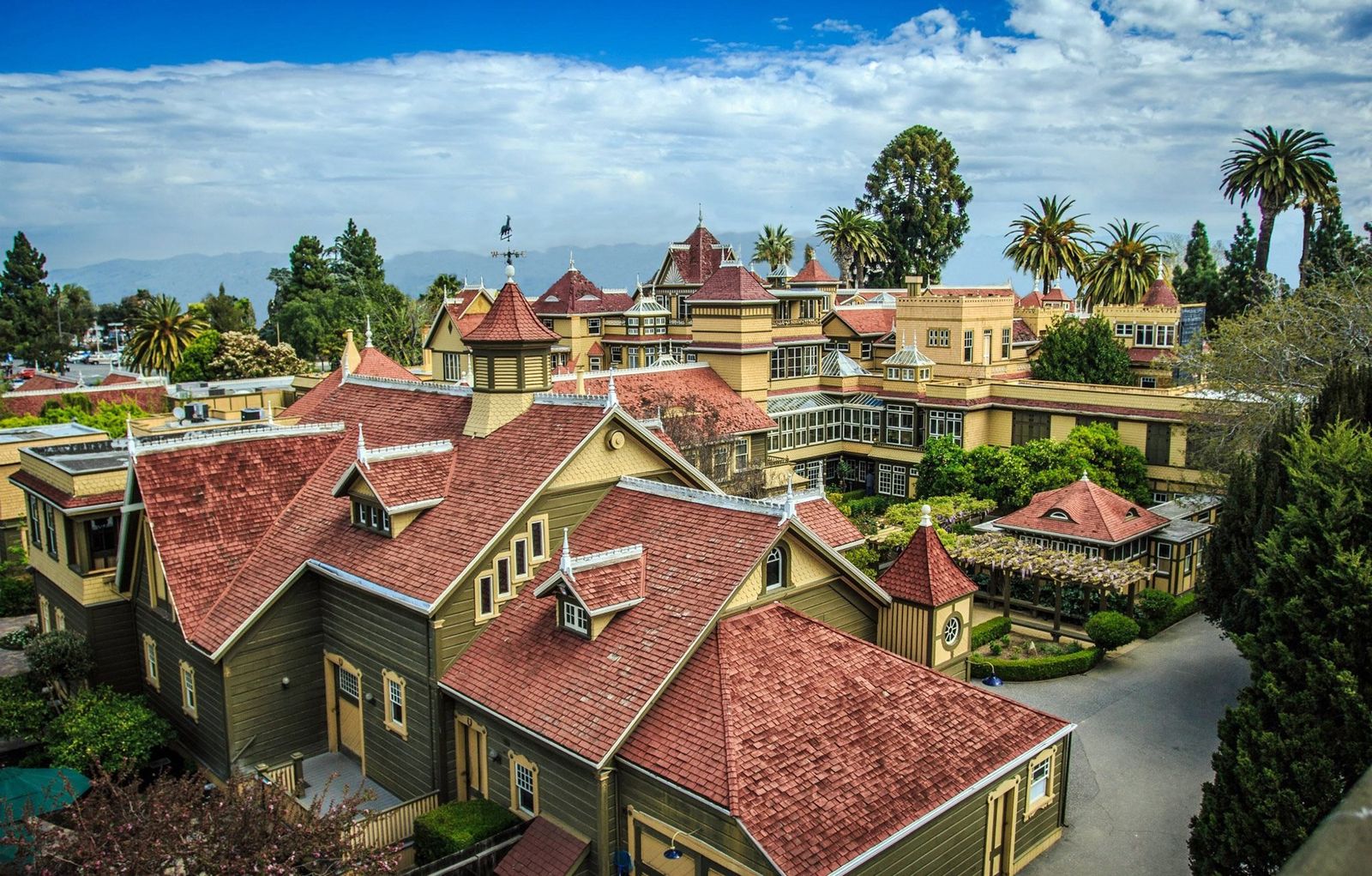 Aerial view of the Winchester Mystery House mansion with its red tile roofs and surrounding trees