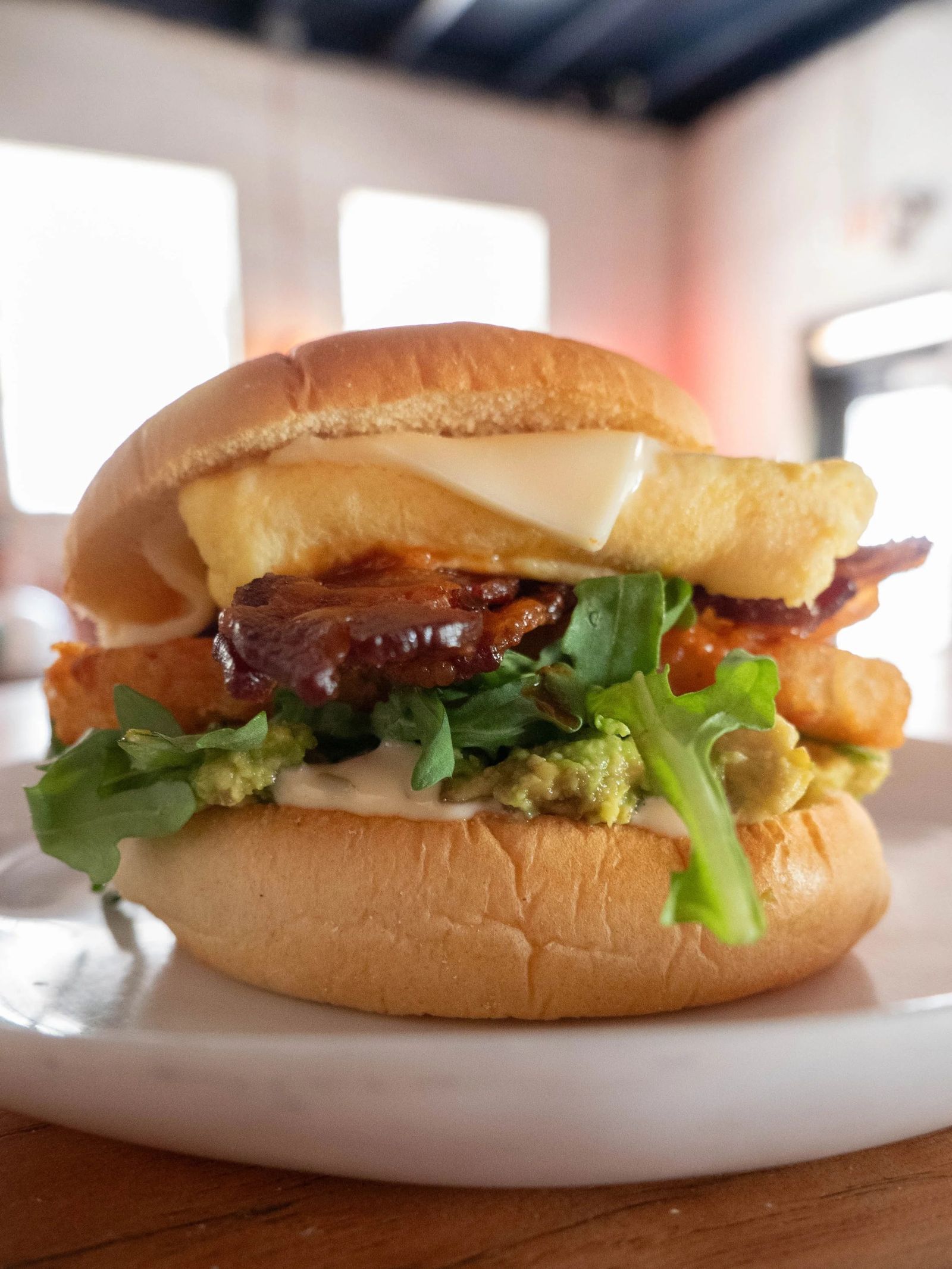 A fried chicken sandwich on a bun with melted cheese.